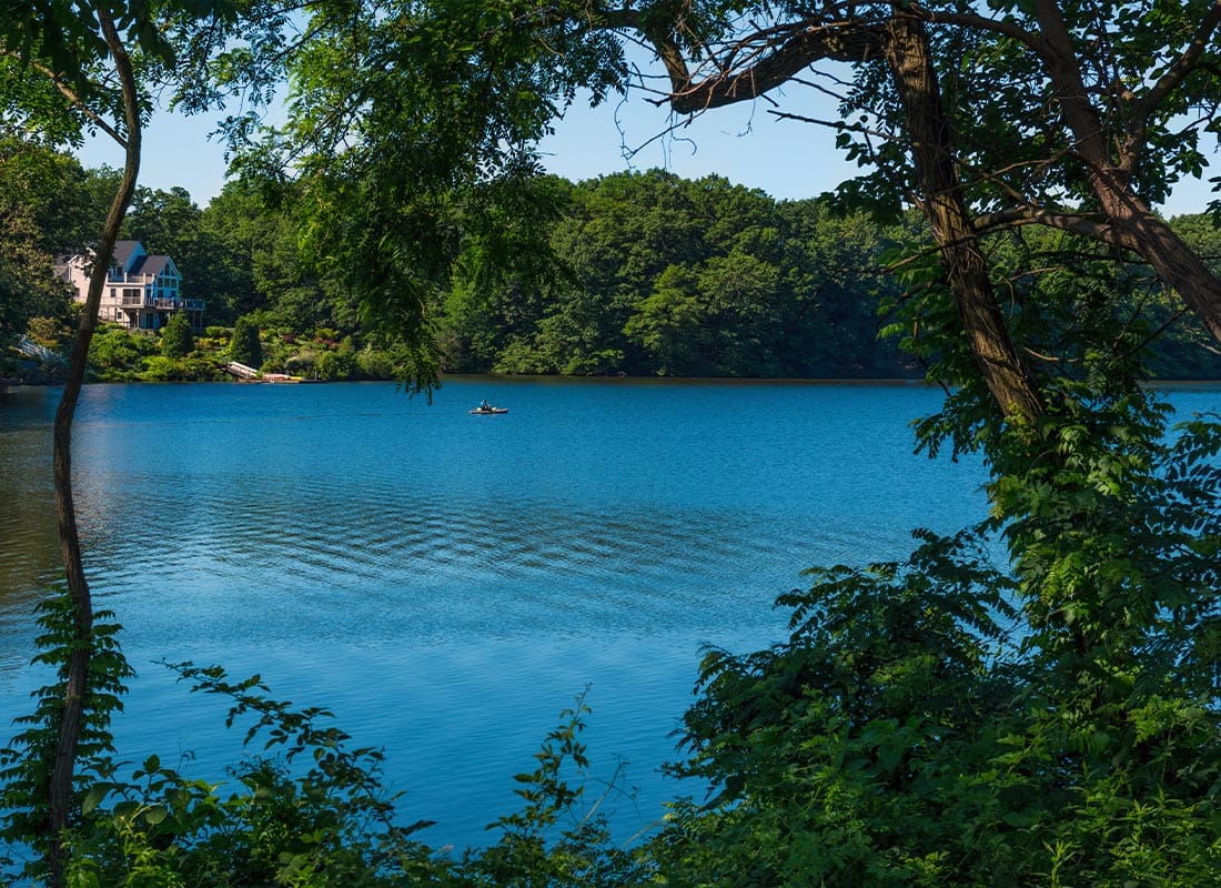 Matawan, NJ - Small Boat on a Rippling Lake With a House in the Background